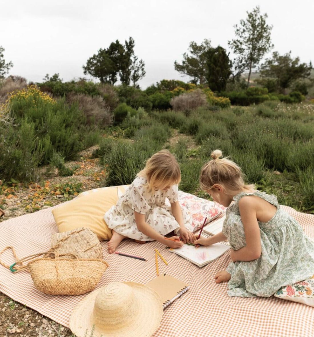 Dos niñas dibujando sobre un mantel, en el campo